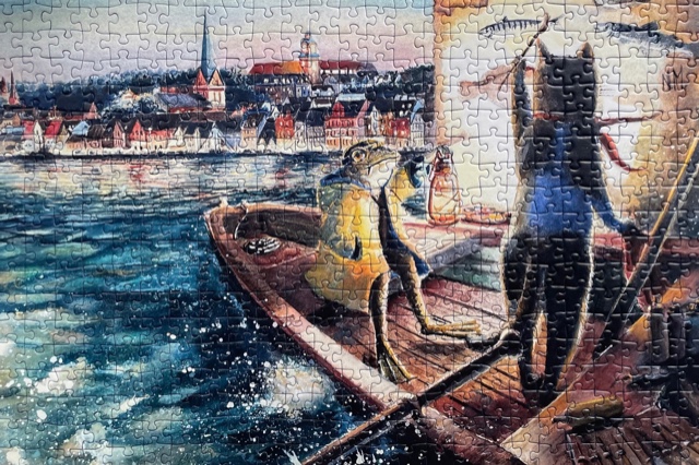 Motiv von N.M. – Eine Katze steht bei Nacht in einem Holzboot im Flensburger Hafen und malt Fische an eine Hauswand. Im Boot dabei sitzt ein Frosch im gelben Regenmantel und hält eine Lampe hoch, damit die Katze etwas sehen kann.