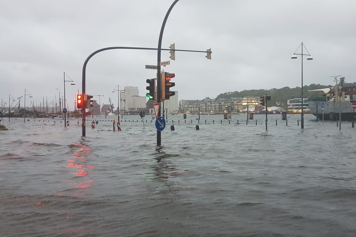 Mehrere Ampeln stehen im Fördewasser, das über die Kaimauer getreten ist.