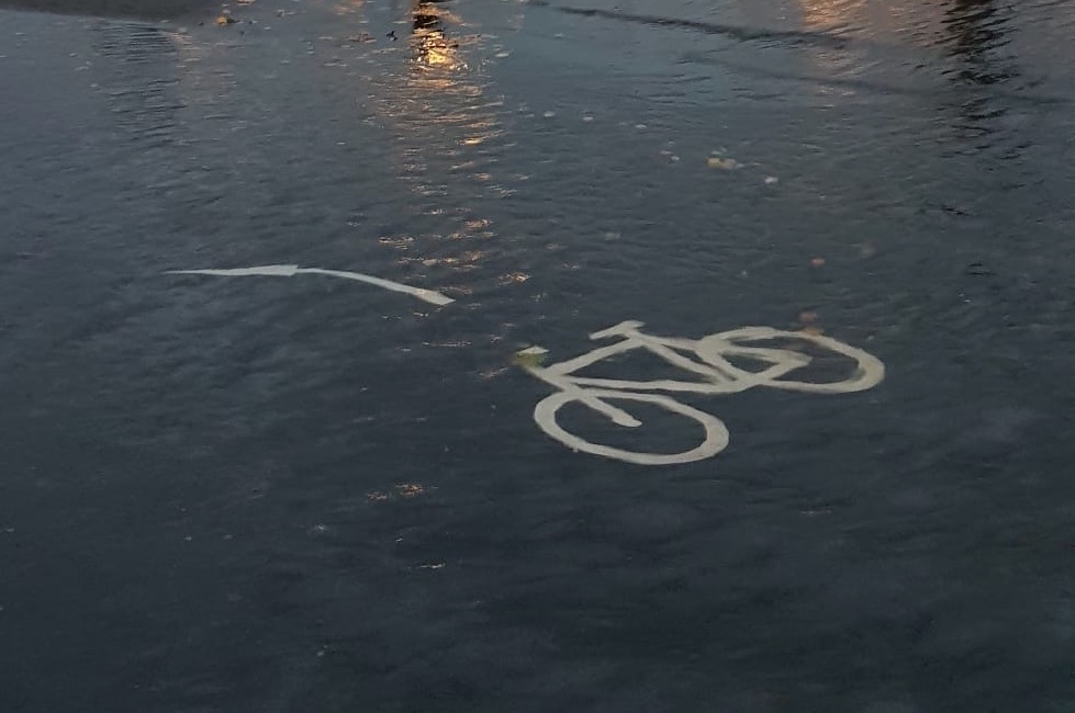 Piktogramm des Fahrradweges ist durch das Wasser auf dem Boden zu sehen.