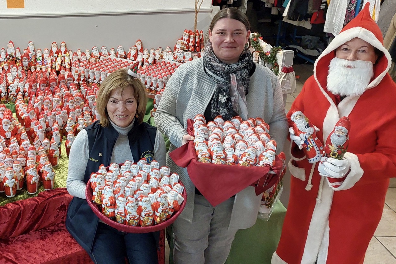 Asta Simon, Catarina Puchleitner und eine als Nikolaus verkleidete Person präsentieren die Schokoladen-Weihnachtsmänner.