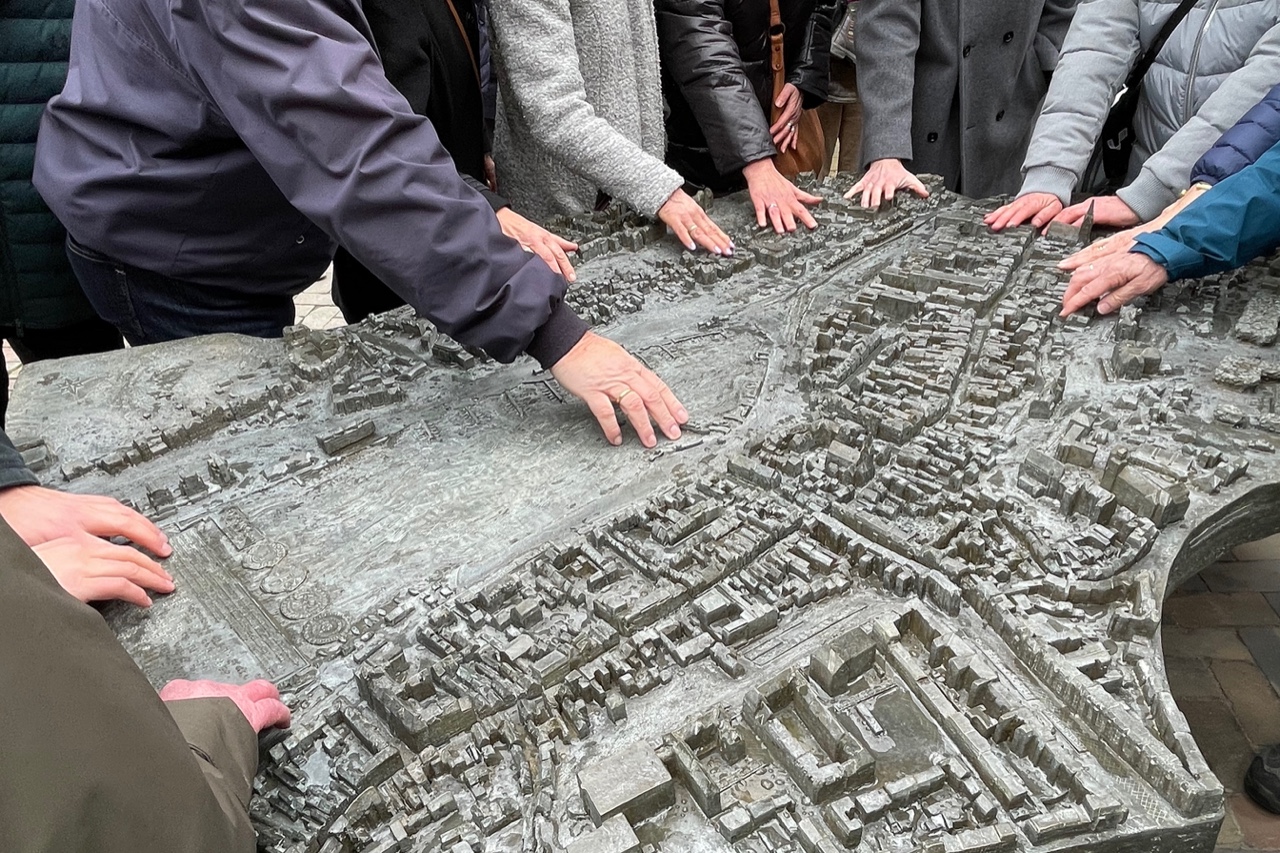 Das Bild zeigt die Unterarme und Hände von sieben Personen, die rund herum um das Stadtmodell stehen und es mit den Fingern erfühlen.