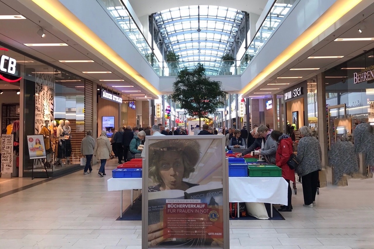 Blick in die Einkaufsmall mit einem Werbeplakat vom Bücherverkauf im Vordergrund. Dahinter der gut besuchte Stand des Bücherverkaufs.