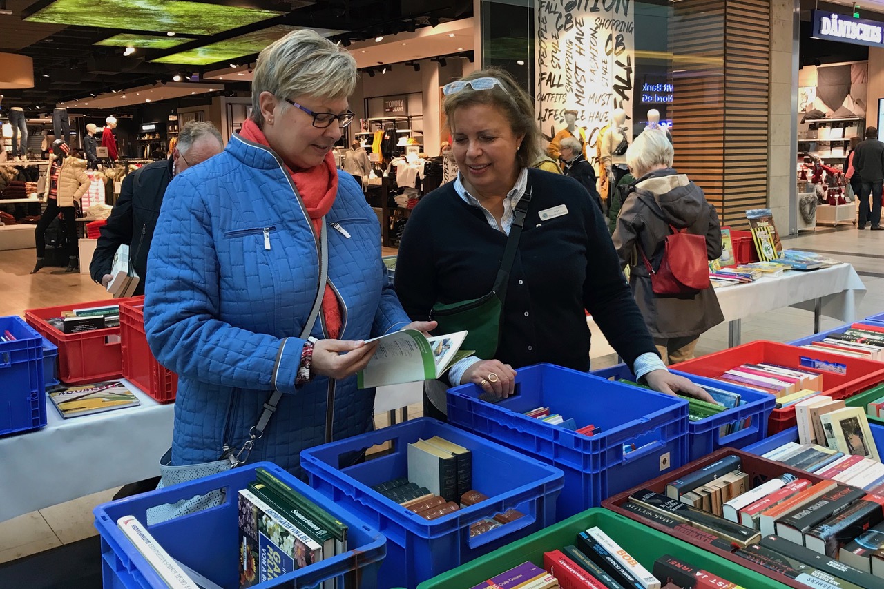 Eine Lionsfreundin berät eine Kundin bei der Auswahl eines Buches