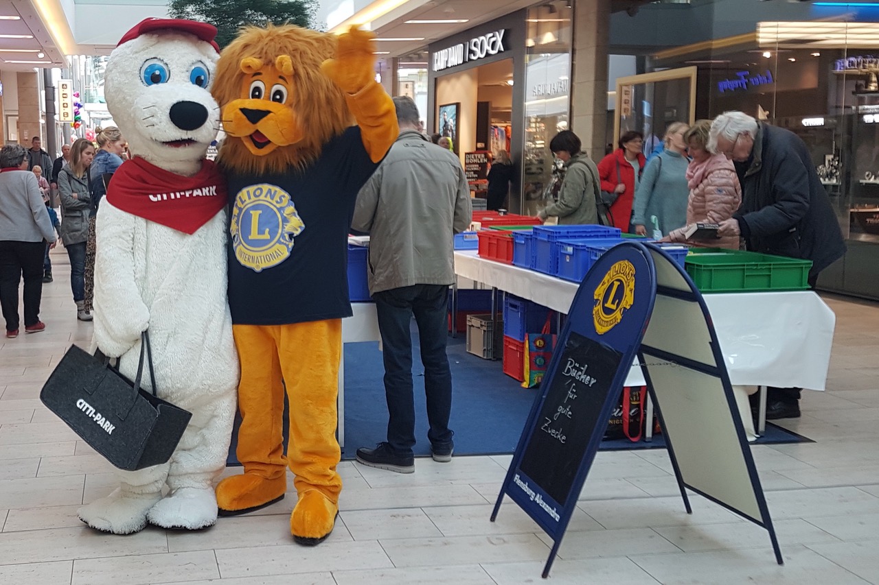 Die Maskottchen Robbe des Citti-Parks und Leo von den Lions treffen sich beim Büchermarkt