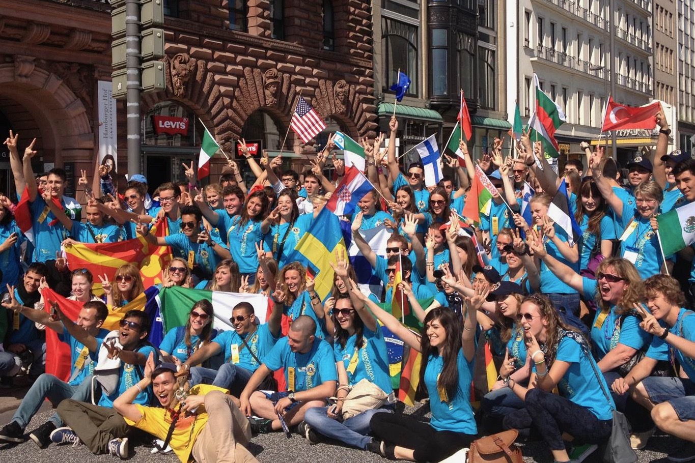 Eine Gruppe junger Menschen posieren zum Gruppenfoto mit ihren jeweiligen Landesfahnen.