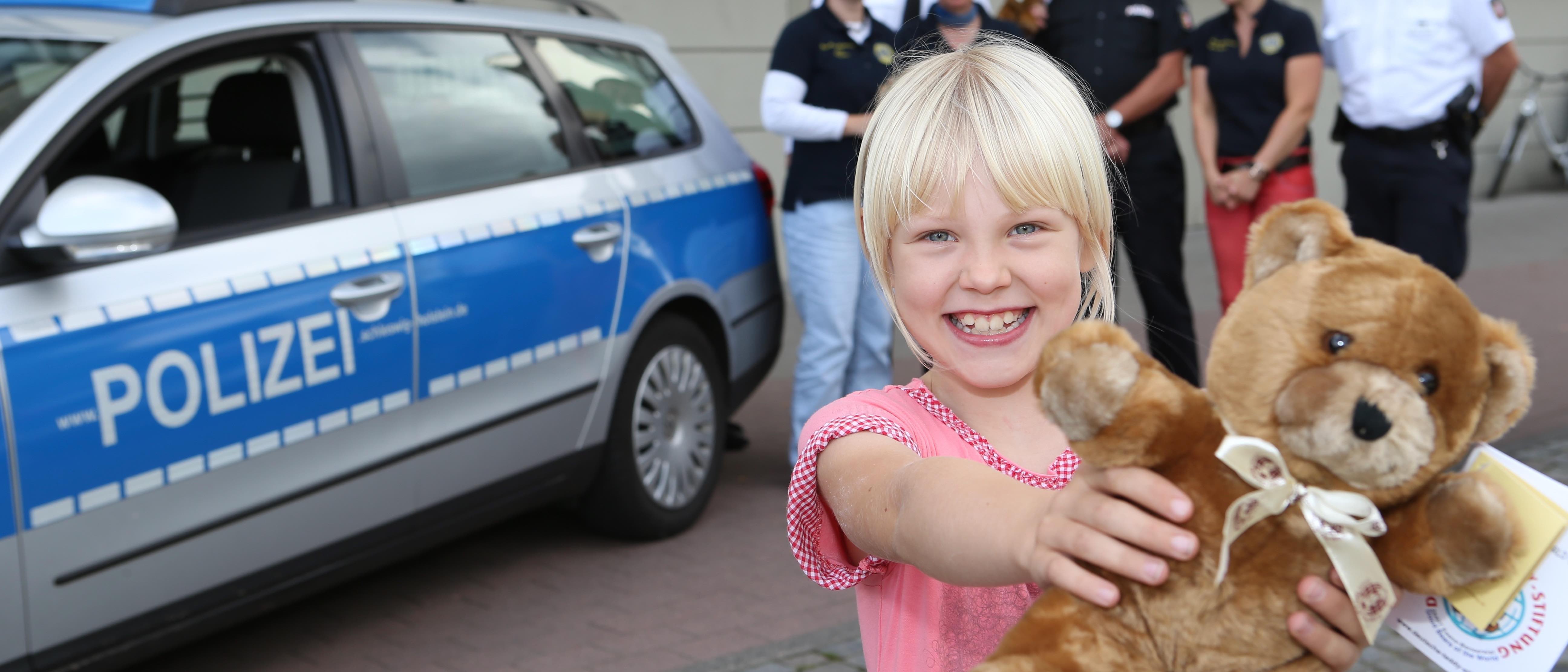 Ein kleines Mädchen zeigt strahlend einen Notfallteddy in die Kamera.