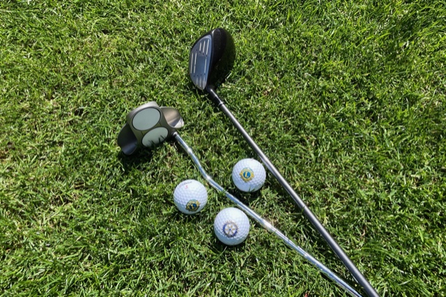 Drei Logo-Golfbälle mit zwei Golfschlägern auf dem Rasen